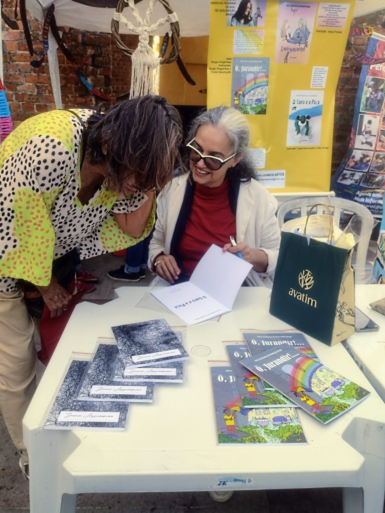 Duaia Assumpção autografa "O Sapo e a Poça" publicado pela Realizamos Artes na FLIST 2022. Sobre a mesa também estão os títulos "Secreta Construção" e "Ô, Jurandir!..." foto Beatriz Varela