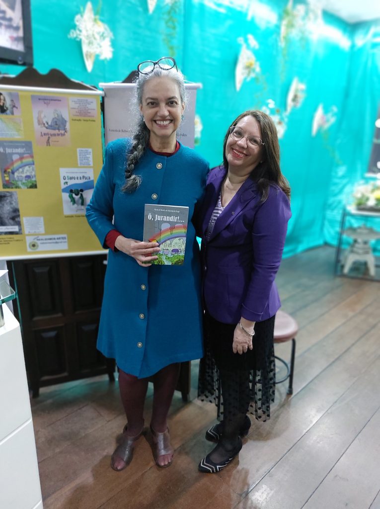 Duaia Assumpção com o livro “Ô, Jurandir!...” de sua autoria na mão e a ministra do Johrei Copa Elyene C. Santos, que é tradutora, e verteu “Ô, Jurandir!...” para o inglês, após a apresentação de 3 HISTÓRIAS DE DUAIA produção da Realizamos Artes, no Johrei Copa, em 7 de setembro de 2023.